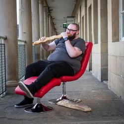 {{ site.name }} sat on a red chair, eating a large baguette