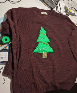 A dark red jumper with chunky knit and a christmas tree design